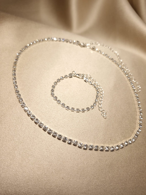 The Lucky Charm Set Tennis clasic, featuring a sparkling colier argintiu and bracelet adorned with strass-uri de zirconiu, is elegantly displayed on silky, beige fabric. They catch the light beautifully, showcasing their brilliance and craftsmanship.